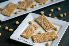 two white plates filled with peanut butter bars on top of a black table next to peanuts