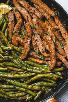 steak and asparagus in a skillet with lemon wedges