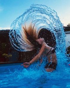 a woman is playing in the pool with her hair blowing out and water splashing on her face