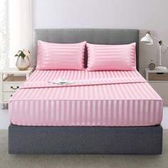 a bed with pink sheets and pillows in a room