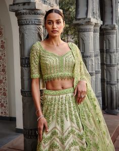 Editor's Note Ivory Tulle Lehenga Choli And Dupatta With A Contrasting Lime Embroidery In Gota, Resham, Crystals, Sequins, And Beads. Color: Ivory Lime Components: Lehenga, Blouse & Dupatta Fabric: Tulle Care: Dry Clean Only About the Designer Nitika Gujral’s journey with designing clothes started almost four decades back while she was still in high school and held her first exhibition for family and friends. Making clothes has been a part of her life ever since. Pista Green Embellished Choli For Wedding, Embellished Pista Green Choli For Wedding, Traditional Embellished Pista Green Gown, Bollywood Style Lace Choli For Reception, Fitted Net Choli With Intricate Embroidery, Fitted Net Sets For Wedding, Embellished Pista Green Wedding Gown, Elegant Pista Green Organza Choli, Lace Choli With Intricate Embroidery For Reception