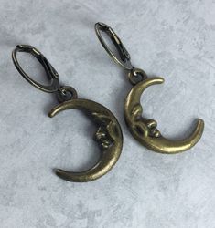 These simple Whimsigoth inspired earrings feature tiny 21x15mm antiqued brass toned crescent moon charms that dangle from 10mm antiqued brass toned round, hoop leverback earwires. Including the earwires, these measure about 1 1/4 inches. I love these moon charms- they have adorable faces etched into them! These would look wonderful paired with a matching antiqued brass toned crescent moon necklace, shown in the last picture, and also available in my shop:  https://www.etsy.com/listing/1308786748/crescent-moon-whimsigoth-necklace-with?ref=listings_manager_grid Thank you so much! Whimsigoth Accessories, Whimsigoth Earrings, Whimsigoth Jewelry, Dark Academia Jewelry, Crescent Moon Necklace, Funky Jewelry, Moon Charm, Moon Earrings, Moon Necklace