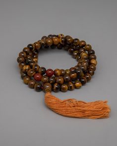 AAA Grade Tiger Eye Japa Mala About our Mala beads Our AAA Grade Brown Tiger Eye Japa Mala handcrafted with 8mm beads, represents spiritual strength and grounding. Each bead, infused with the captivating colors of brown Tiger Eye, exudes protection and vitality, guiding you on a journey of inner transformation and empowerment. Carnelian dividers are delicately incorporated into this mala, adding to its beauty and functionality by providing a seamless transition between beads and infusing your me Brown Spiritual Beads For Meditation, Spiritual Mala With 108 Beads For Blessing, Hand-strung Spiritual Beads For Blessing, Spiritual Wooden Beads Jewelry For Meditation, Spiritual Brown Beaded Bracelets, Spiritual Gemstone Beaded Bracelets For Meditation, Holistic Healing Mala With Wooden Beads, Spiritual Healing Brown Beads, Spiritual Wooden Beaded Healing Bracelets