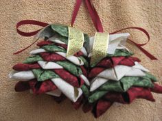 a pine cone ornament hanging from a red ribbon on a tan towel covered in white and green fabric