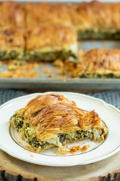 a piece of quiche on a white plate next to a baking pan with the casserole in it