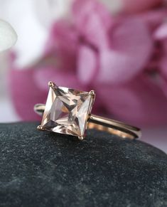 a close up of a ring on a rock with flowers in the background