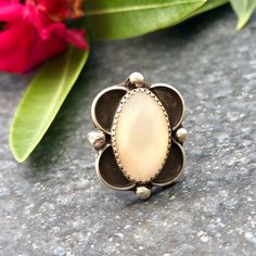 This beautiful ring features a center oval mother of pearl stone set in a saw tooth bezel. The stone is placed in a shadow box design with hand carved silver around the face of the stone. The stone has a pretty iridescent look to it. Mother of pearl is the inner layer of shells of oysters or mollusks and is known to have a calming effect. Metal: Sterling Silver  Stone: Mother of Pearl  Size: 5 Dimensions: Length 1", Width 15/16" Always Free Shipping in the US Please let me know if you have any questions! Thank you for shopping with EraofJewelry! Be sure to check out our store daily for more beautiful added pieces! Sincerely, Era of Jewelry Oval Concho Jewelry Gift, Southwestern Jewelry, White Band, Pearl Size, Stone Settings, Sterling Ring, Mother Of Pearl, Shadow Box, Beautiful Rings