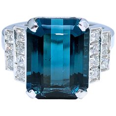 an aqua and white gold ring with diamonds on the sides, surrounded by blue stones