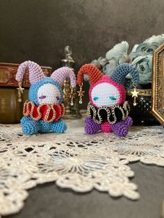 two small crocheted animals sitting next to each other on a lace doily