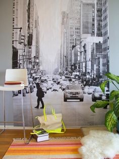 a living room with a large city scene on the wall and a rug in front of it