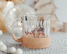 a close up of a coffee mug on a table with white and gold balls in the background