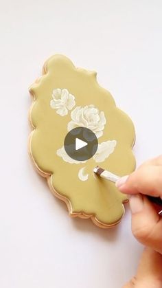 someone is using a marker to paint the flowers on a flower shaped broochle