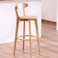 a wooden bar stool with a green cushion on the seat and back rest in front of a white kitchen counter