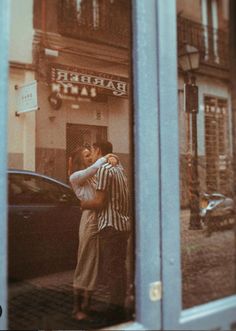 two people standing in front of a store window