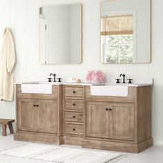 a bathroom with two sinks, mirrors and a bench in front of the sink area