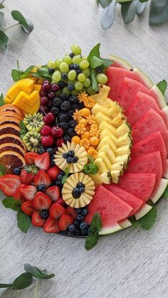 a platter filled with watermelon, grapes, strawberries and other fruits