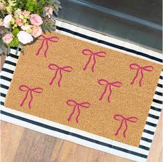 a door mat with pink bows on it next to flowers and a potted plant