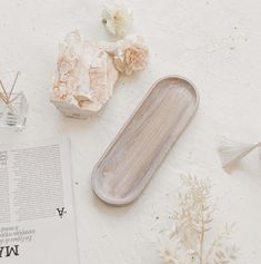 a wooden tray sitting on top of a table next to flowers and a glass vase