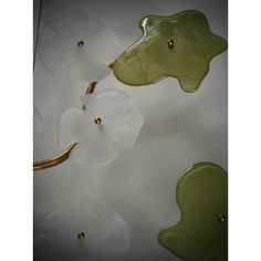 three green and white flower shaped glass pieces on a tablecloth with gold beads around them