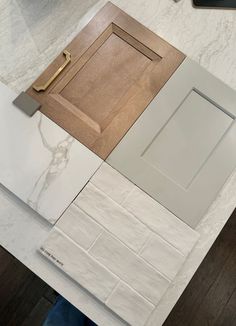 a kitchen counter top with white marble and wooden cabinet doors on each side, next to a phone