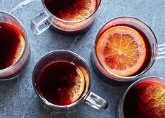 three glasses filled with liquid sitting on top of a counter next to sliced oranges