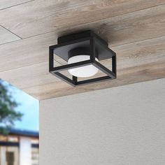 an outdoor ceiling light mounted on the side of a house with wood paneling and white walls