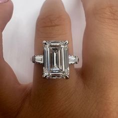 a woman's engagement ring with an emerald and baguettes on the side