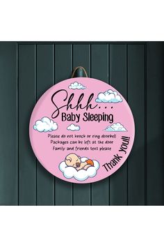 a pink sign hanging from the side of a wall with clouds and baby sleeping on it