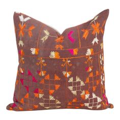 an orange and pink decorative pillow on a white background