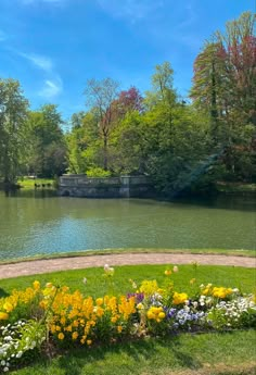 the park is full of colorful flowers and trees, along with a lake in the background