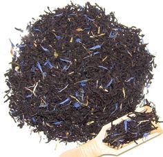 a pile of black tea next to a wooden spoon