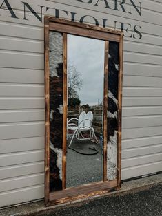 a mirror sitting on the side of a building with cow print covering it's frame