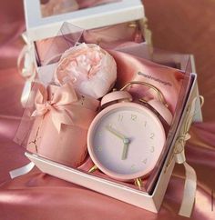 a pink clock and some flowers in a box