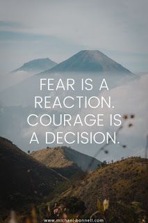 the words fear is a reaction, courage is a decision on top of a mountain