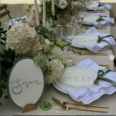 the table is set with white flowers and place cards