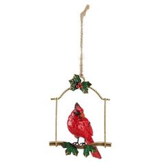 a red bird sitting on top of a tree branch hanging from a metal frame with holly leaves