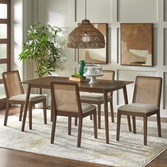 a dining room table with four chairs and a potted plant in the middle of it