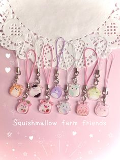 a bunch of key chains hanging from the side of a pink background with words sushimallow farm friends on it