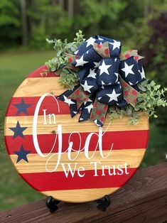 a wooden sign with the words in god we trust on it and an american flag bow