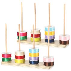 several rolls of colored tape are on wooden holders with toothpicks in the middle