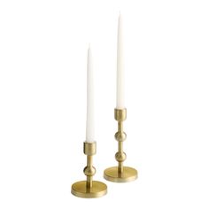 two white candles sitting next to each other on top of a metal stand with one candle in the middle