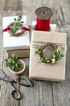 three wrapped presents sitting on top of a wooden table next to scissors and twine