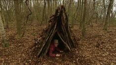 a person sitting in front of a teepee in the middle of a forest filled with leaves