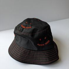 Paul Smith Black & Orange 'Happy' Bucket Hat. Great Condition - Never Worn. Size Small. Unisex. Cut From 100%, Breathable Cotton, This Black Bucket Hat Features A Repeated Ps 'Happy' Embroidered Pattern On The Front, In Orange. With Its Tonal Colouring, This Hat Is An Ideal Transitional Piece For The Changing Seasons. Casual Orange Bucket Hat With Short Brim, Trendy Orange Adjustable Bucket Hat, Casual Adjustable Orange Bucket Hat, Adjustable Orange Cotton Bucket Hat, Adjustable Orange Bucket Hat, Black Bucket Hat For Spring, Trendy Orange Cotton Hat, Black Cotton Hat, Black Bucket Hat