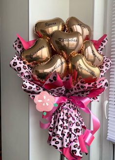 a bunch of gold heart shaped balloons tied to a white door with pink and leopard print ribbon