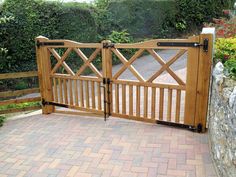 a wooden gate is open on the side of a brick walkway in front of a stone wall