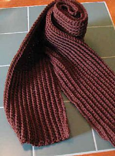 a red knitted scarf laying on top of a tiled floor