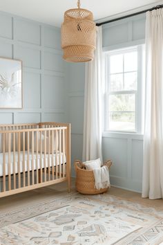 a baby's room with blue walls and white curtains