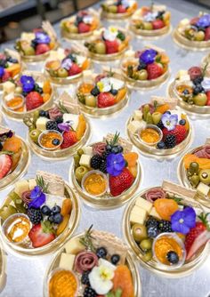 many small trays filled with different types of fruits and cheese on top of a table