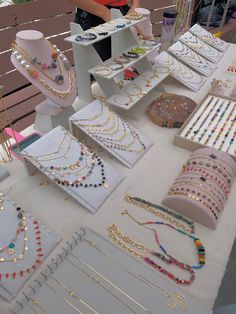 a table topped with lots of different types of necklaces and bracelets on display